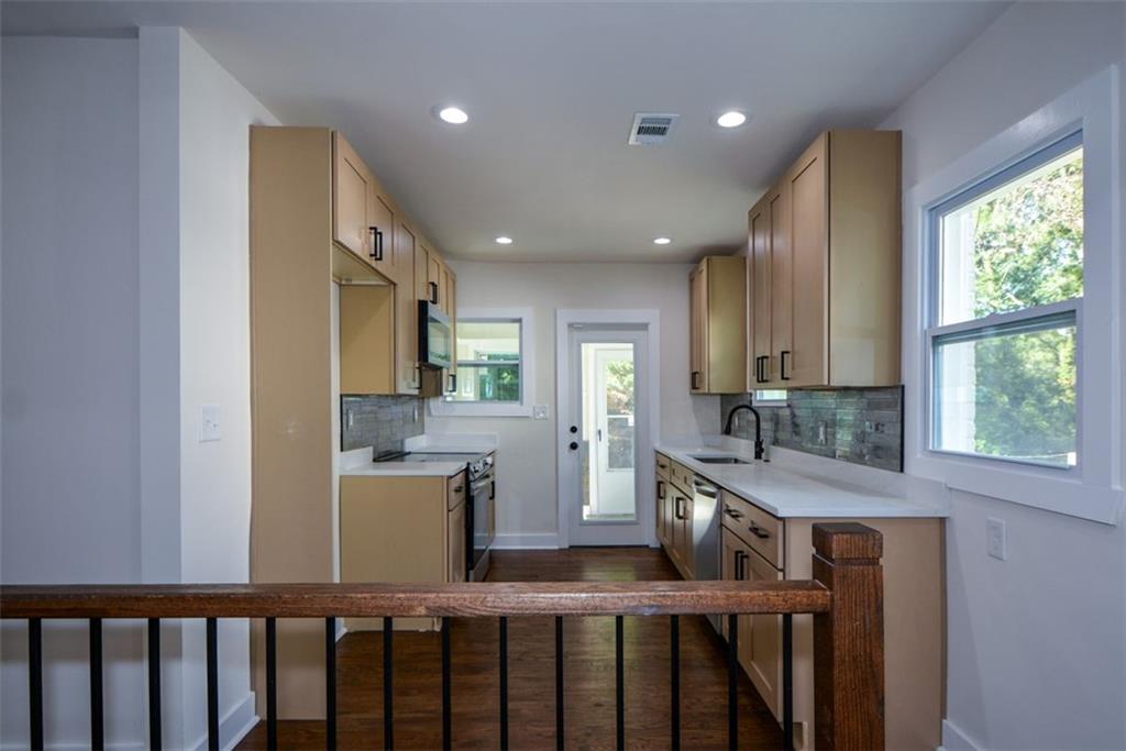 1275 Westridge Road Southwest Atlanta, GA 30311 - Photo 10 of 38 a kitchen with stainless steel appliances granite countertop a refrigerator a sink dishwasher a stove and a dining table with wooden floor