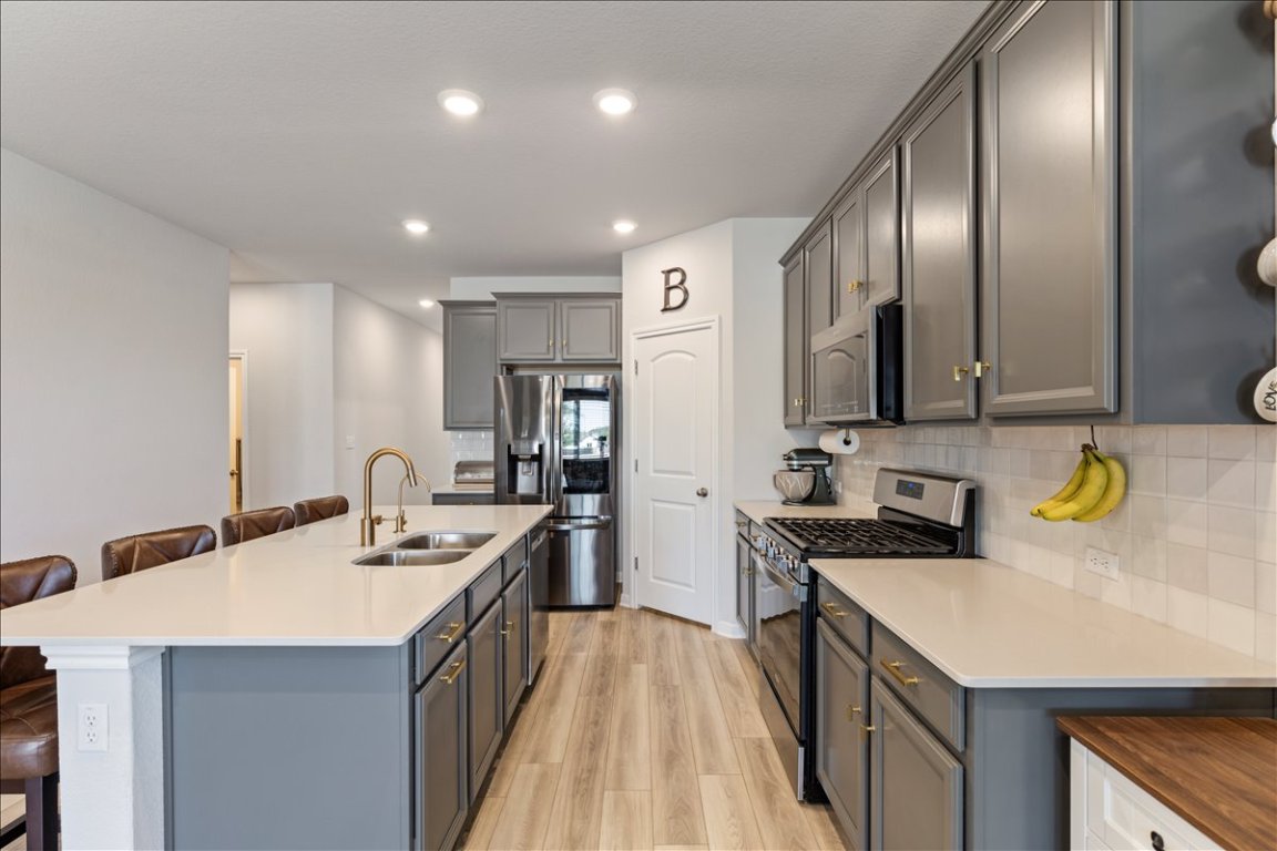 1001 A Dog Iron Street Georgetown, TX 78633 - Photo 6 of 25 a kitchen with a sink a counter top space a stove and a refrigerator