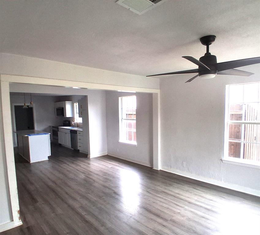 820 Allen Street Denton, TX 76205 - Photo 4 of 14 an empty room with wooden floor kitchen view and windows