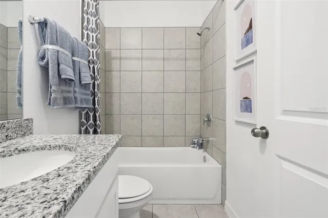 a bathroom with a granite countertop bathtub sink vanity and toilet