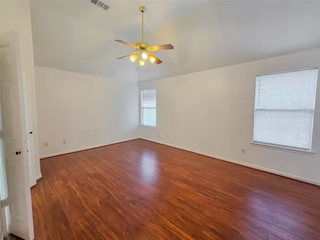 a view of an empty room with a window and wooden floor