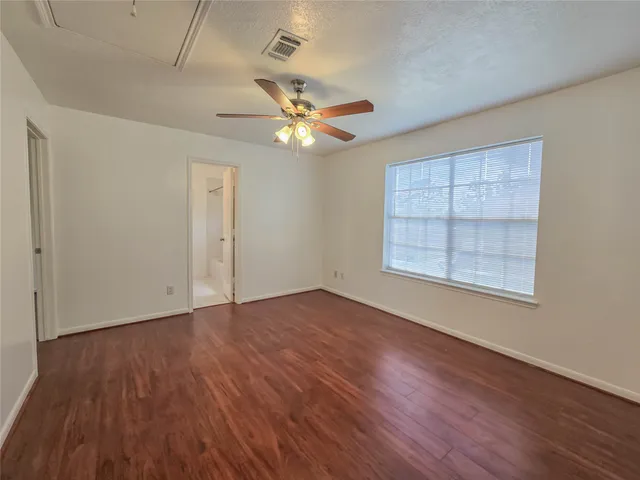 an empty room with wooden floor chandelier fan and windows