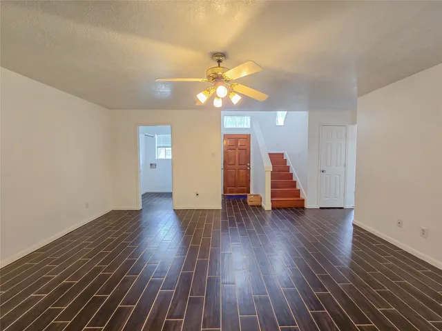 a view of a room with wooden floor ceiling fan and window