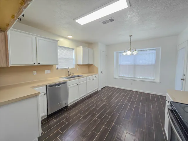 a kitchen with wooden floors and white cabinets