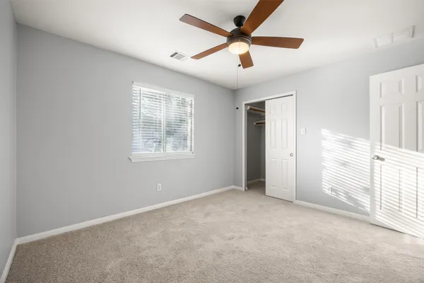 an empty room with windows and fan