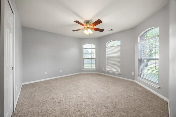 a view of an empty room with window and chandelier fan
