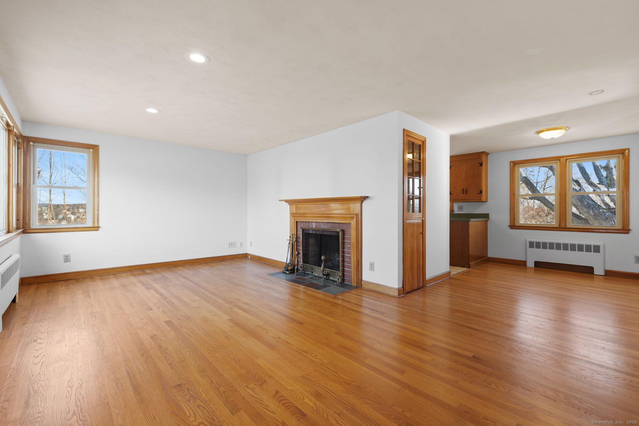 95 Tuttle Street Bristol, CT 06010 - Photo 6 of 28 an empty room with wooden floor fireplace and windows