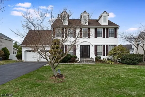 a front view of a house with garden and trees