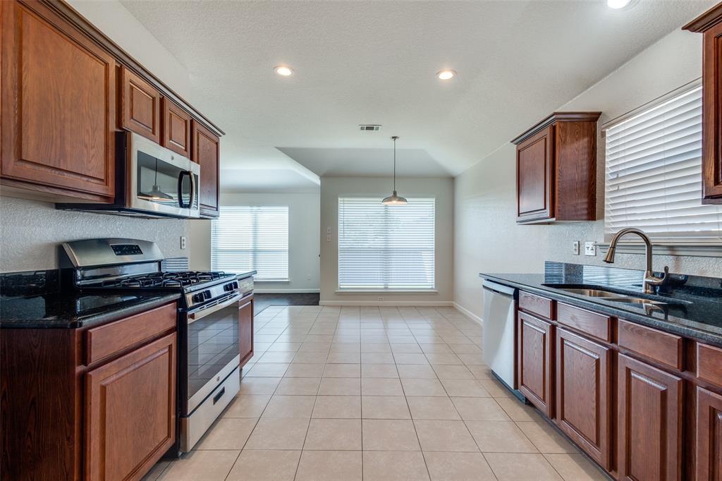 1257 Barrel Run Fort Worth, TX 76052 - Photo 12 of 26 Kitchen featuring wood cabinetry, stainless steel appliances, granite countertops, and tile flooring