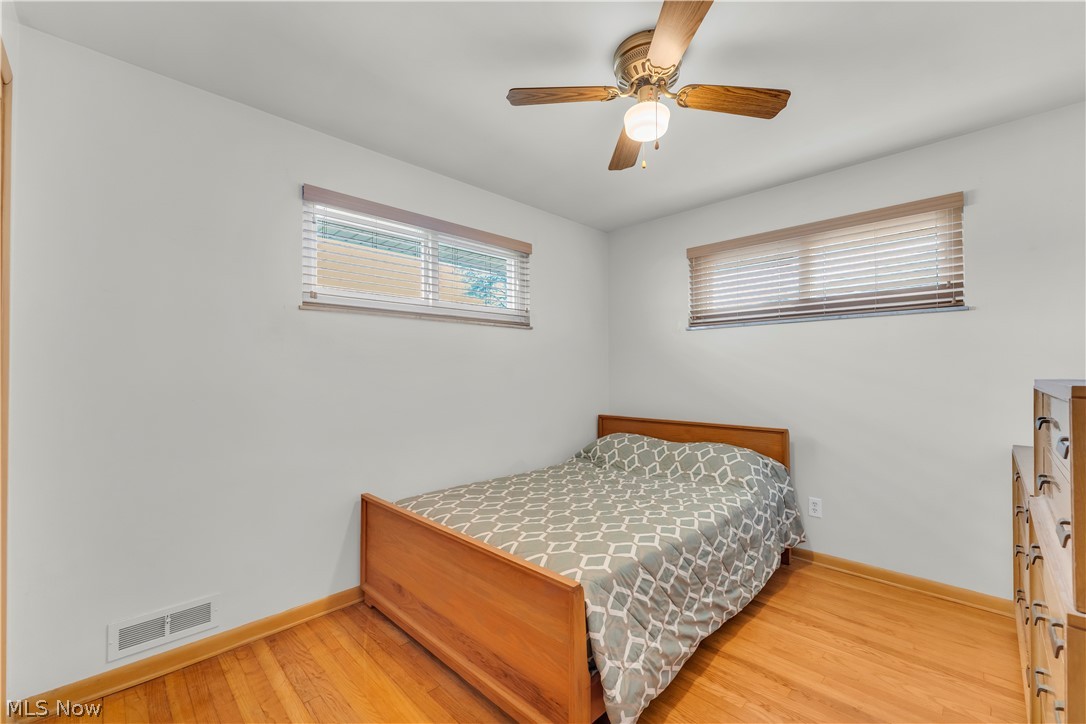 3023 Norris Avenue Cleveland, OH 44134 - Photo 23 of 41 Hardwood flooring paired with white walls, two windows, and a ceiling fan with light fixture