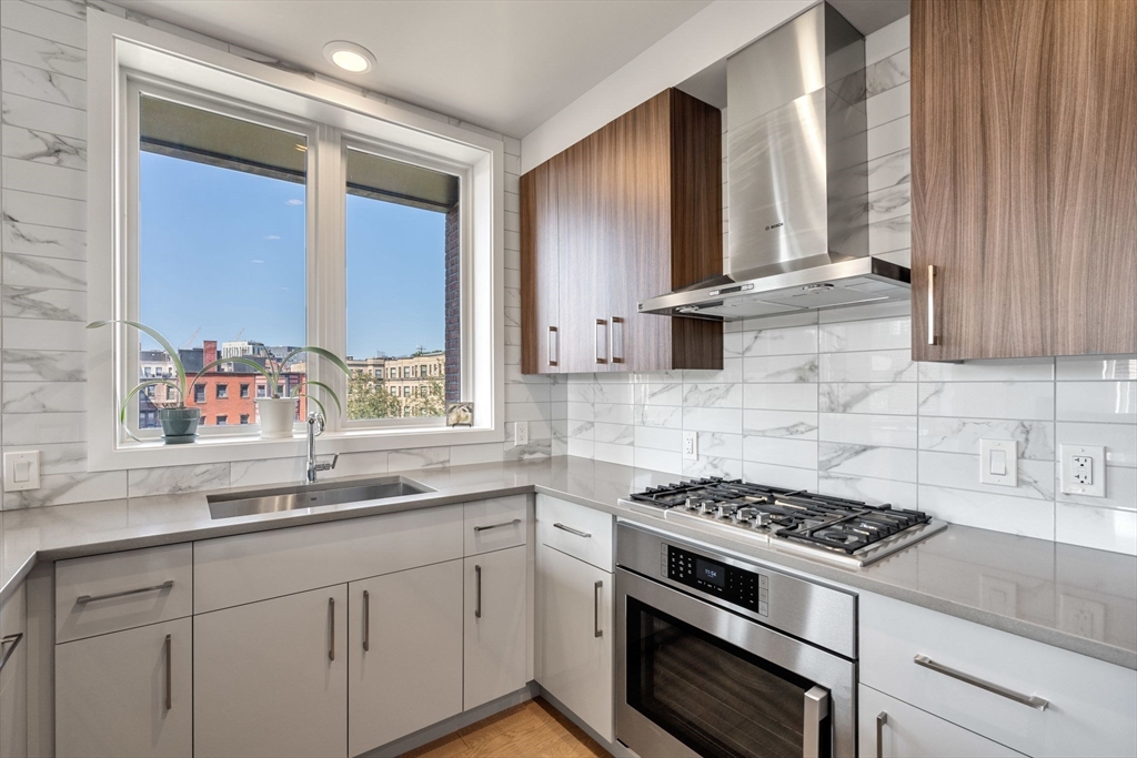 44-50 Symphony Road, Unit 403 Boston, MA 02115 - Photo 20 of 28 a kitchen with stainless steel appliances a sink a stove and a window