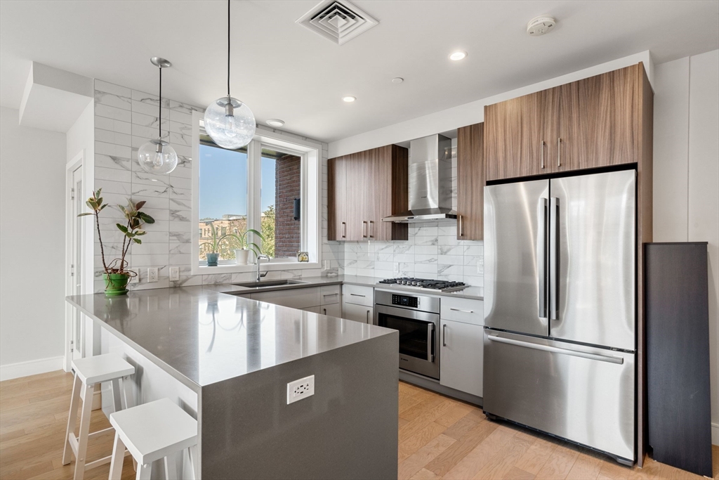 44-50 Symphony Road, Unit 403 Boston, MA 02115 - Photo 6 of 28 a kitchen with kitchen island a counter space a sink and stainless steel appliances