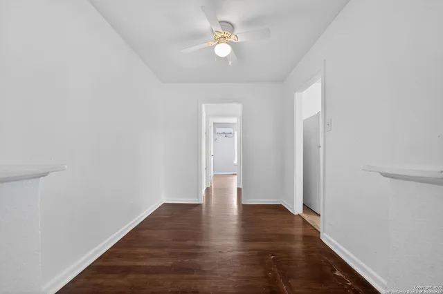 a view of an empty room with window and wooden floor