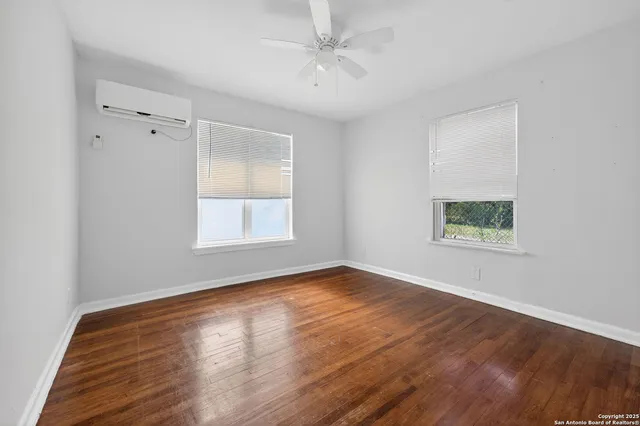 a view of an empty room with wooden floor and a window