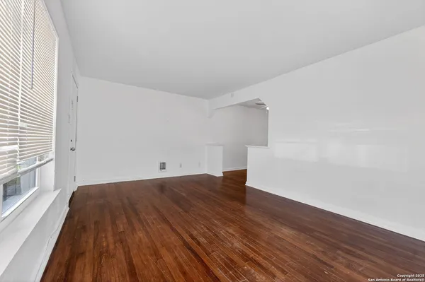a view of a big room with wooden floor and windows