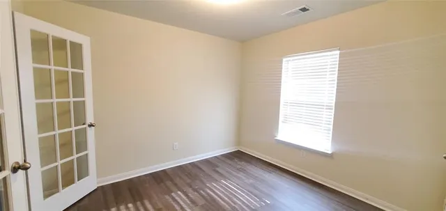 a view of an empty room with a window and wooden floor