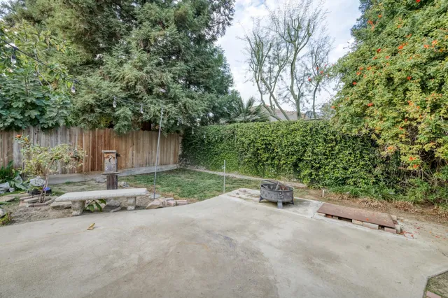 a backyard of a house with table and chairs under an umbrella