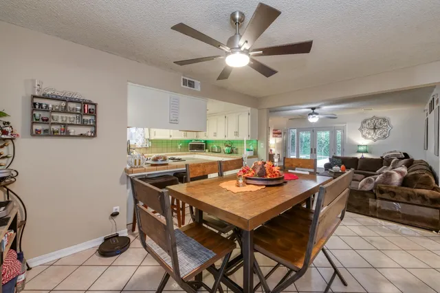 a kitchen with a stove a refrigerator and a dining table with wooden floor