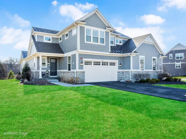 a front view of a house with a yard and large trees