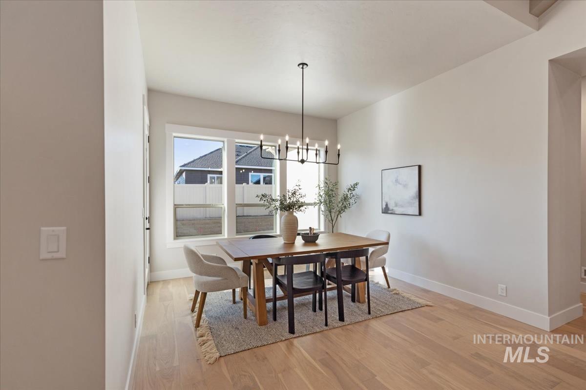 7355 Powell Place Eagle, ID 83714 - Photo 14 of 37 Dining area featuring wood-finish flooring, a contemporary chandelier, large windows with white trim, and light-toned walls
