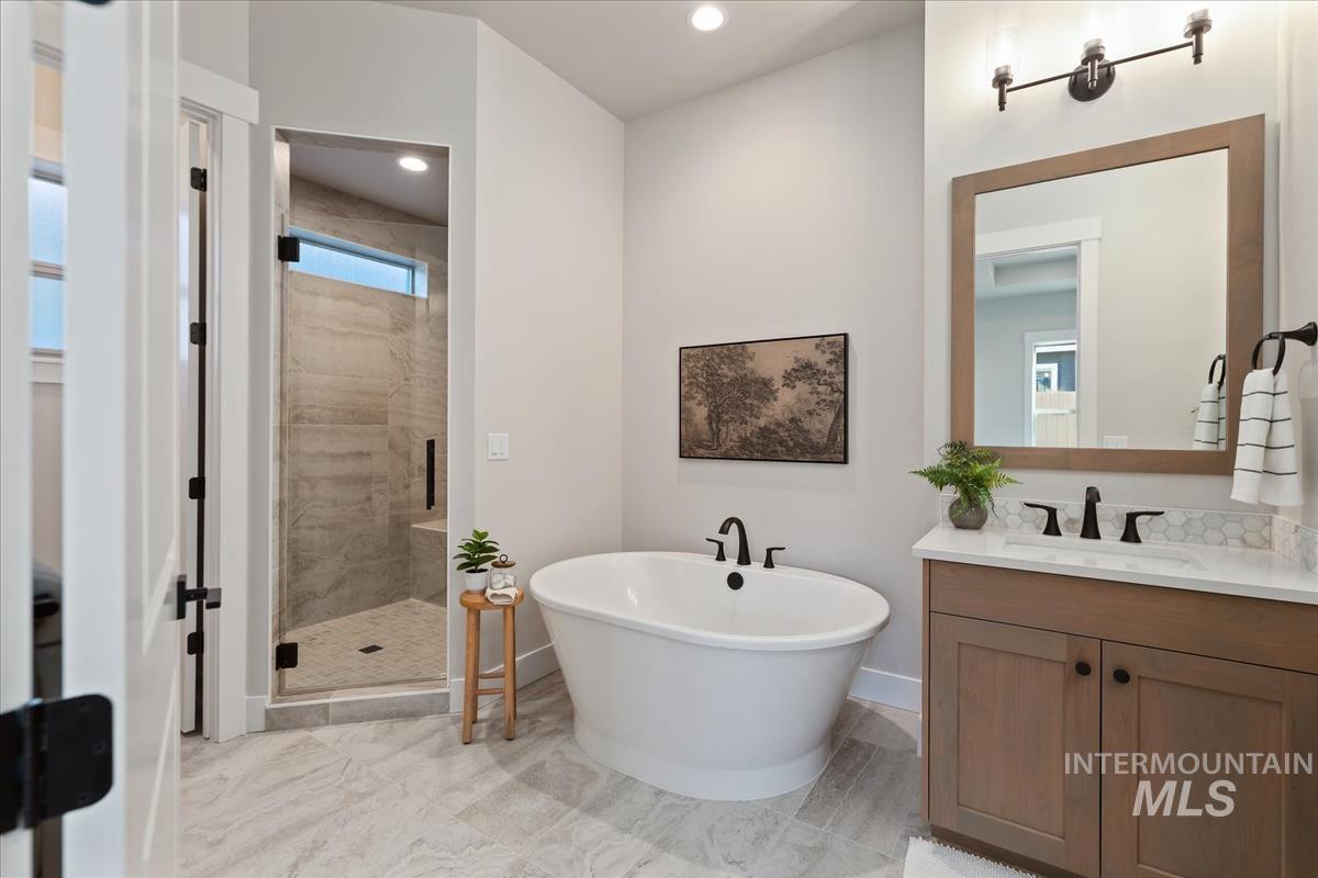 7355 Powell Place Eagle, ID 83714 - Photo 19 of 37 Freestanding soaking tub with matte black fixtures, set against light gray wall paint and large format floor tiling