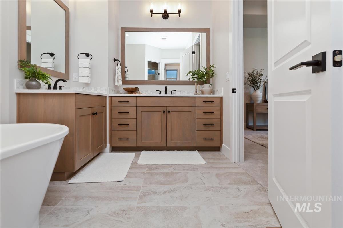 7355 Powell Place Eagle, ID 83714 - Photo 20 of 37 Bathroom featuring a freestanding white tub, dual wood-finish vanity with stone countertops, and tile flooring