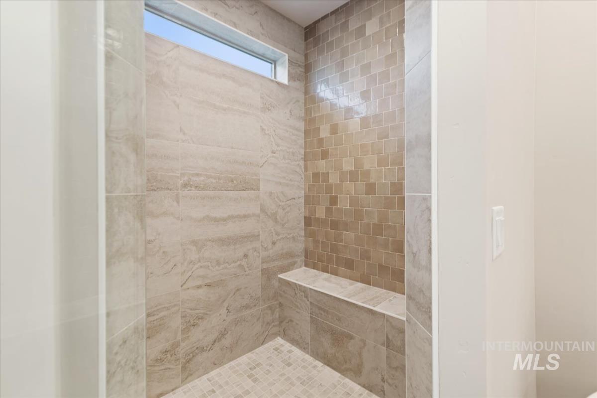 7355 Powell Place Eagle, ID 83714 - Photo 22 of 37 Walk-in shower featuring large format wall tiling, a mosaic tile accent wall, built-in bench seating, mosaic floor tiling, and a high horizontal window