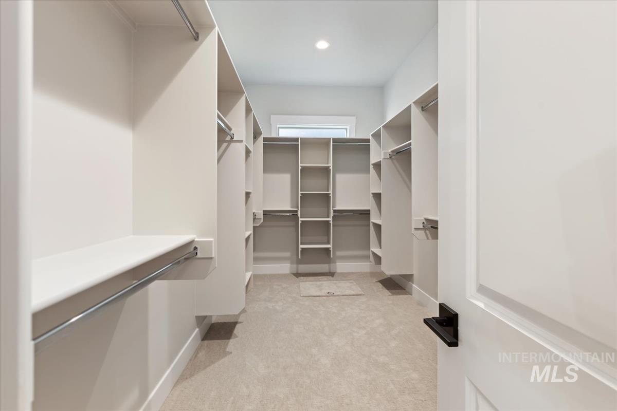7355 Powell Place Eagle, ID 83714 - Photo 23 of 37 Expansive walk-in closet featuring extensive built-in shelving, multiple hanging rods, recessed lighting, and soft carpet flooring