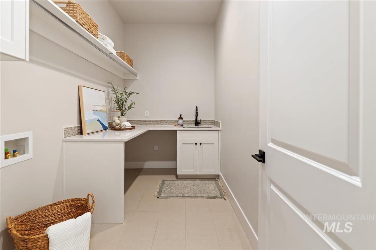 7355 Powell Place Eagle, ID 83714 - Photo 31 of 37 Utility room featuring white cabinetry, a built-in countertop with an undermount sink, a wall-mounted shelf, and light-colored tile flooring