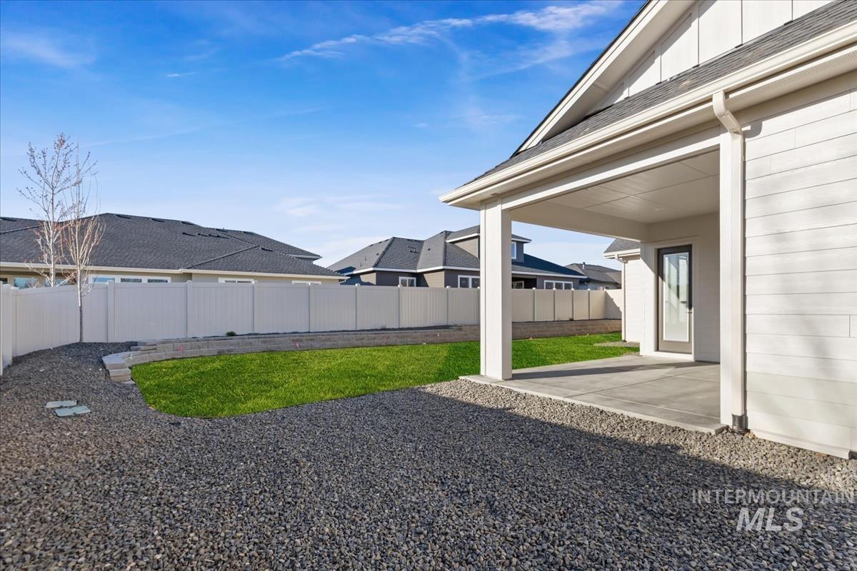 7355 Powell Place Eagle, ID 83714 - Photo 33 of 37 Expansive covered patio with concrete slab, gravel landscaping, and a manicured lawn