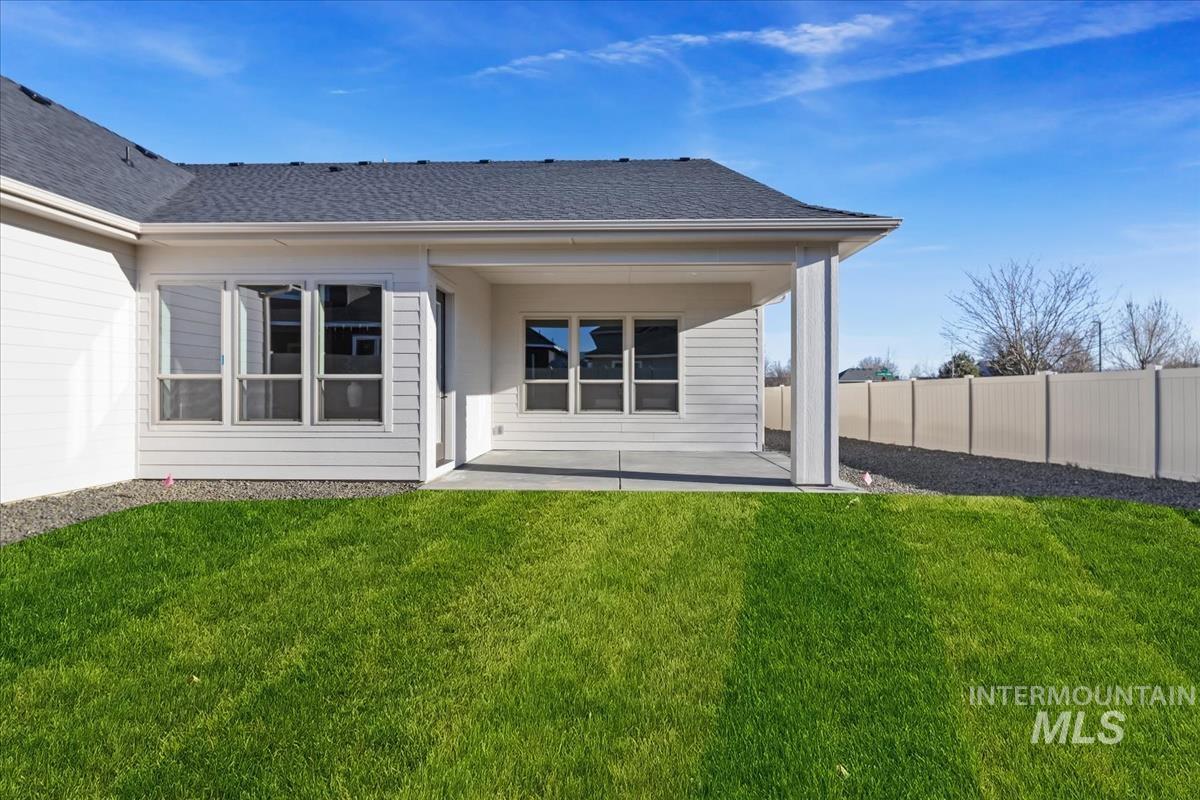 7355 Powell Place Eagle, ID 83714 - Photo 35 of 37 Expansive green lawn with a covered concrete patio, white vinyl siding, multiple windows, and a dark shingle roof
