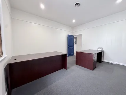a view of a hallway with wooden floor and a bathroom