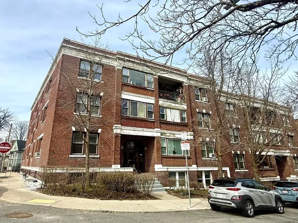 a front view of a building with lot of cars and trees
