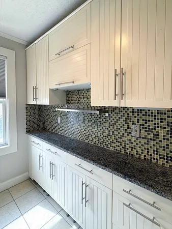 a kitchen with granite countertop white cabinets and black appliances