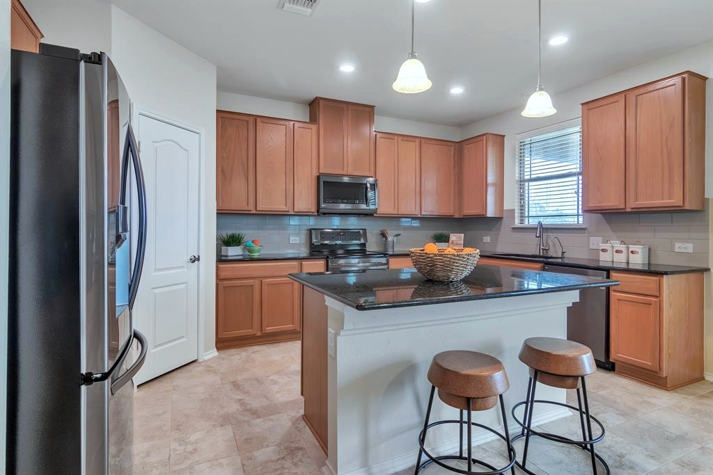1075 Toltec Trail Georgetown, TX 78626 - Photo 5 of 32 a kitchen with stainless steel appliances granite countertop a refrigerator stove a sink and a microwave