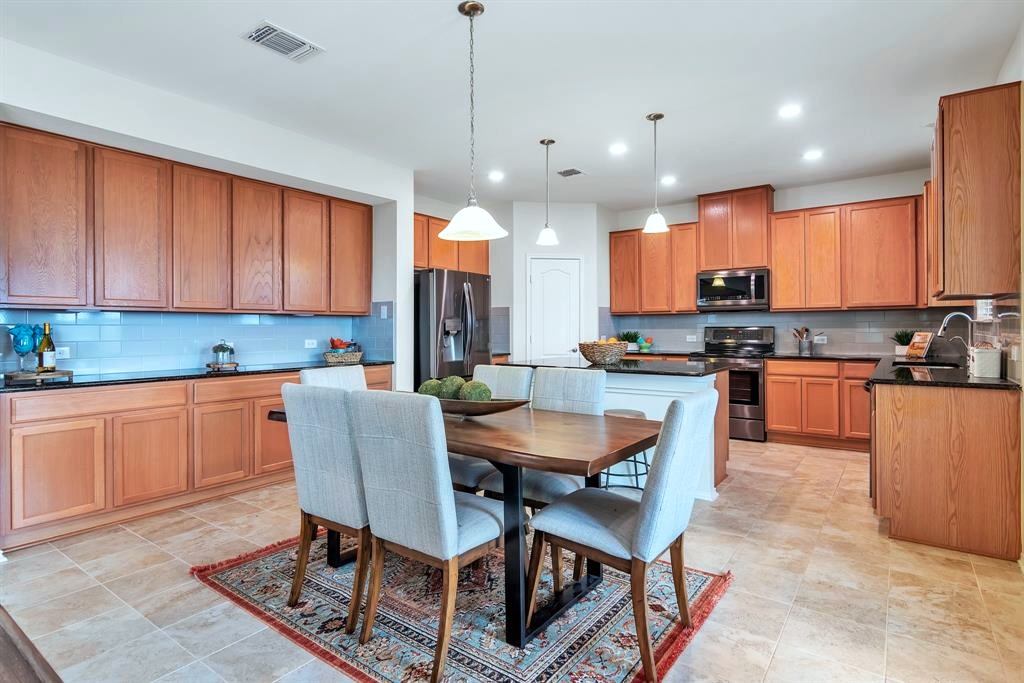 1075 Toltec Trail Georgetown, TX 78626 - Photo 6 of 32 a kitchen with stainless steel appliances granite countertop a stove a sink a kitchen island with a dining table and chair