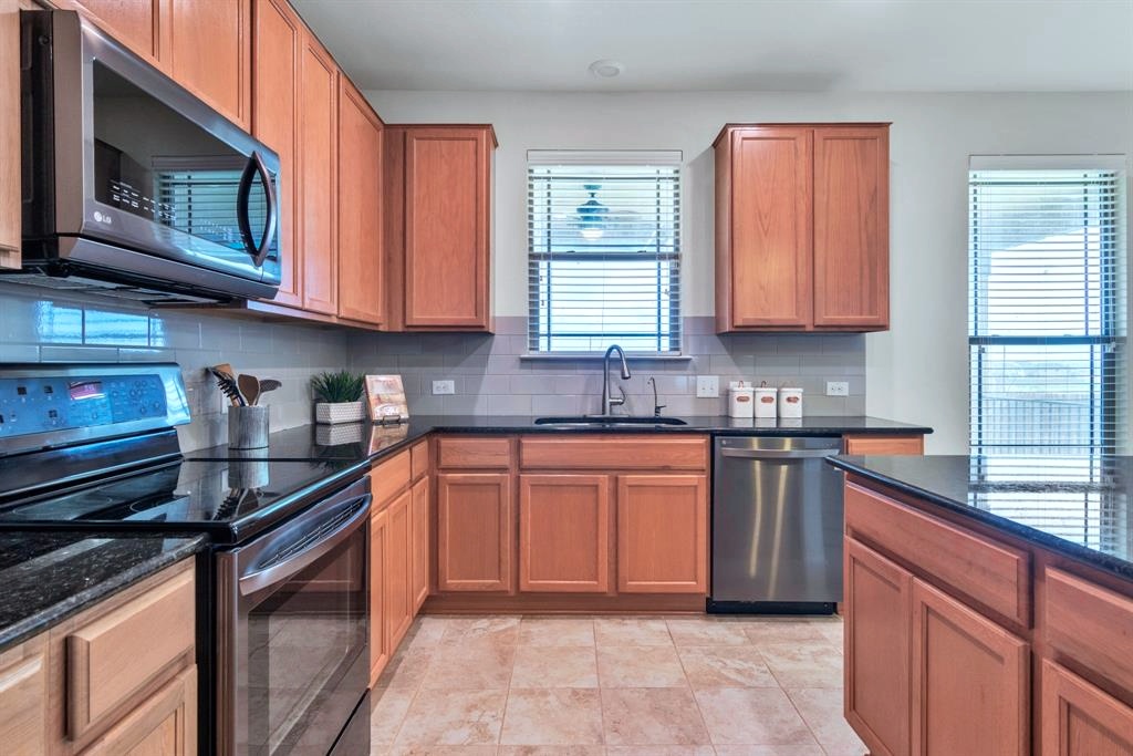 1075 Toltec Trail Georgetown, TX 78626 - Photo 8 of 32 a kitchen with stainless steel appliances granite countertop a stove sink microwave and window