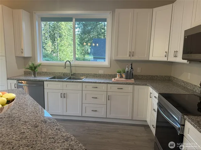 a kitchen with granite countertop a sink window and cabinets