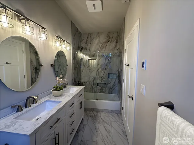 a bathroom with a double vanity sink mirror and shower