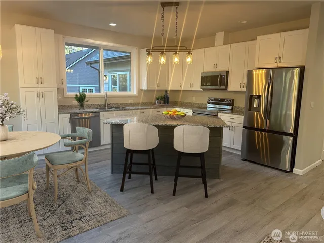 a kitchen with stainless steel appliances granite countertop a table chairs refrigerator and sink