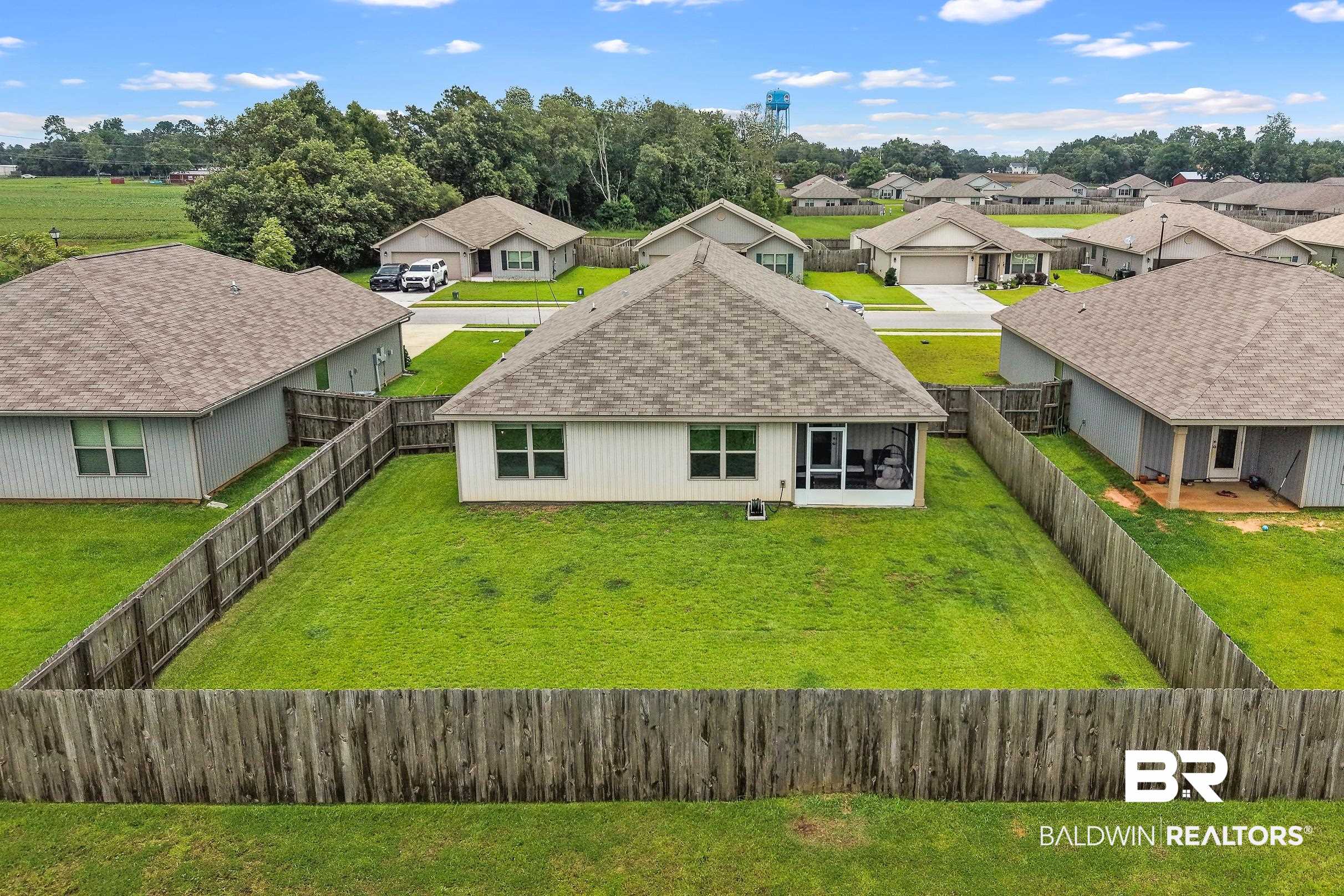32030 Terranova Loop Lillian, AL 36549 - Photo 23 of 30 Fenced backyard featuring a manicured lawn, screened porch, and a water tower in the distance