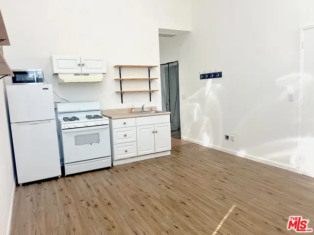 a kitchen with stainless steel appliances a white stove top and wooden floors