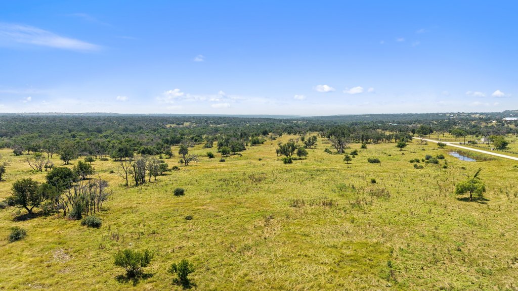 Tbd Reeh Road Fredericksburg, TX 78624 - Photo 22 of 37 Rolling green landscape dotted with mature trees under an expansive blue sky offers tranquil country living.