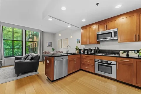 a kitchen with stainless steel appliances granite countertop a stove top oven a sink dishwasher a microwave oven and a dining table with garden view