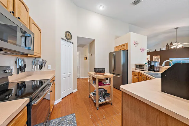 a kitchen with stainless steel appliances kitchen island granite countertop a refrigerator a stove and a sink with wooden floor