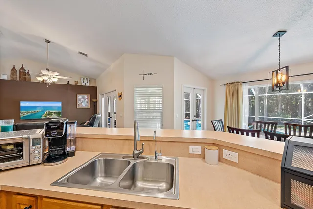 a kitchen with a sink a counter top space and living room view