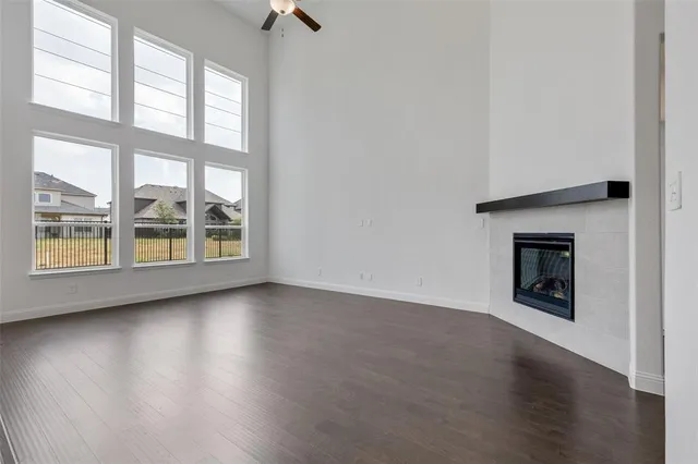 an empty room with wooden floor fireplace and windows