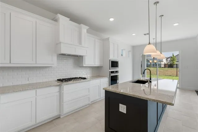 a kitchen with kitchen island granite countertop a sink a stove and cabinets