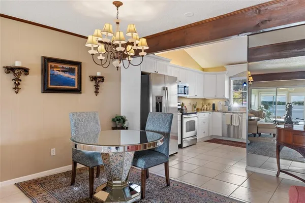 a dining room filled chandelier and kitchen view