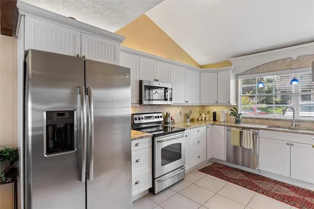 a kitchen with white cabinets stainless steel appliances and a window